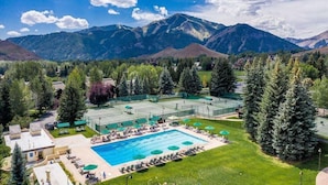 A resort with a swimming pool, tennis courts, and a mountain backdrop. - Wildwood Cottage at Villager + SV Resort Amenities (Sun Valley)