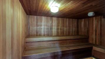 A wooden sauna with a sloped ceiling and a light fixture.