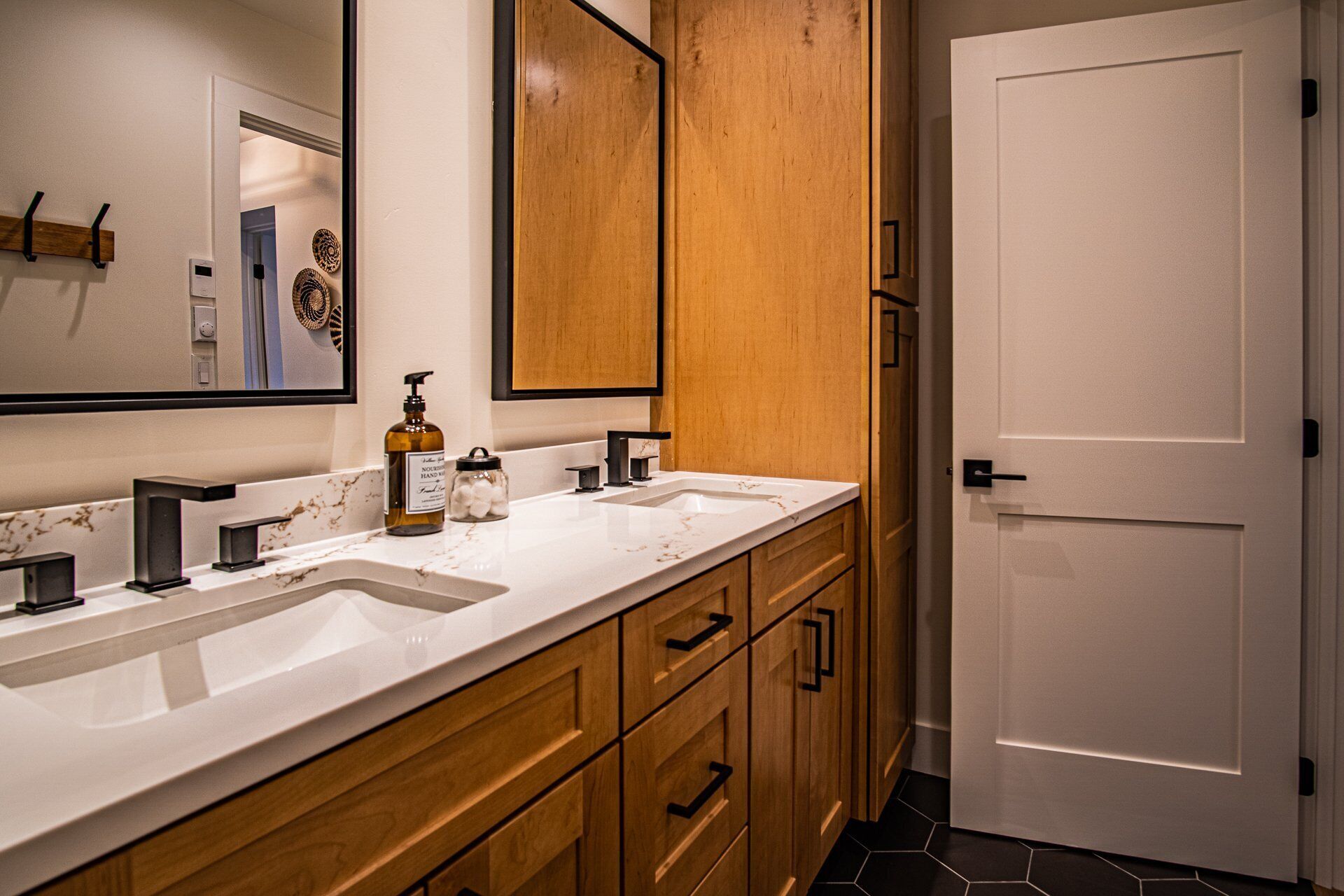 A modern bathroom with two sinks, wooden cabinets, and a large mirror.