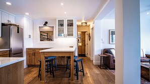 Een moderne keuken met houten kastjes, een inbouw eiland met barkrukken en een koelkast.