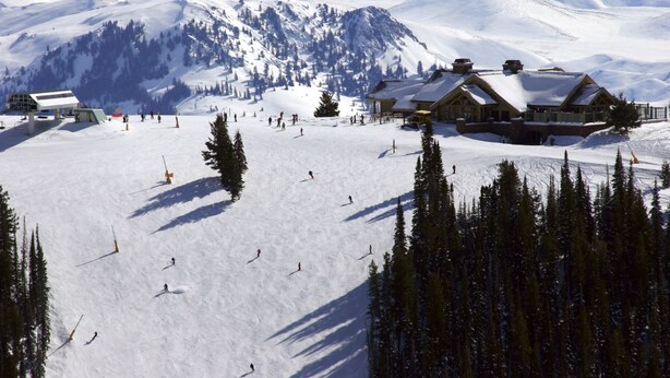 Une station de ski dotée de plusieurs chalets, de nombreuses pistes de ski et offrant un paysage montagneux en toile de fond.