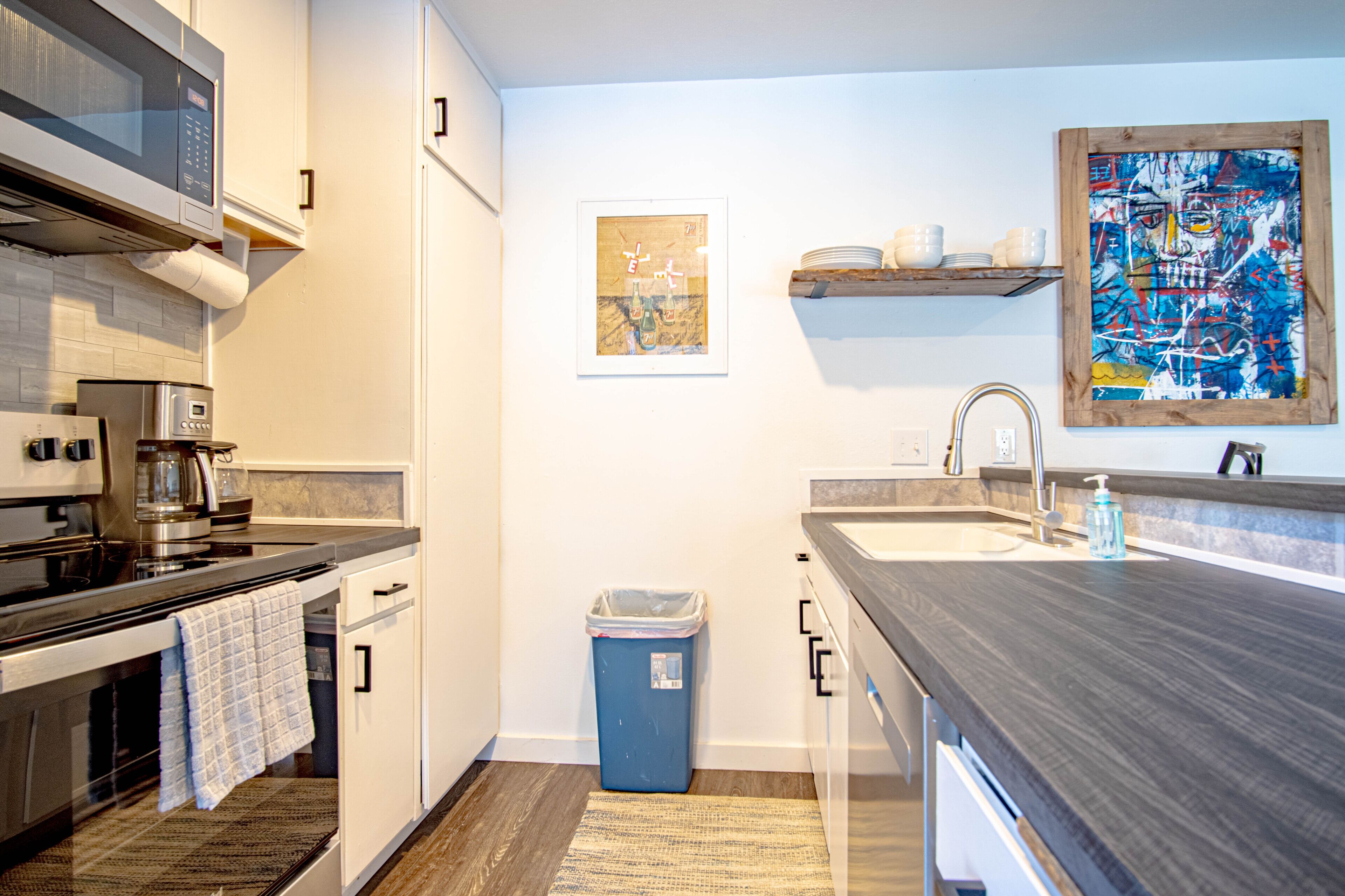 A modern kitchen with stainless steel appliances, a wooden countertop, and a trash bin.