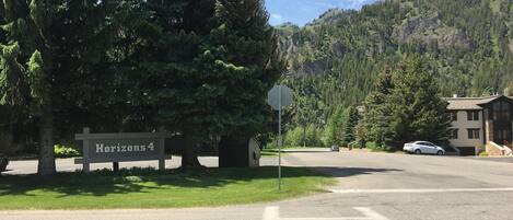 A road sign reading "Horizons 4" with a stop sign nearby, a building with a stone facade, and a mountain backdrop.