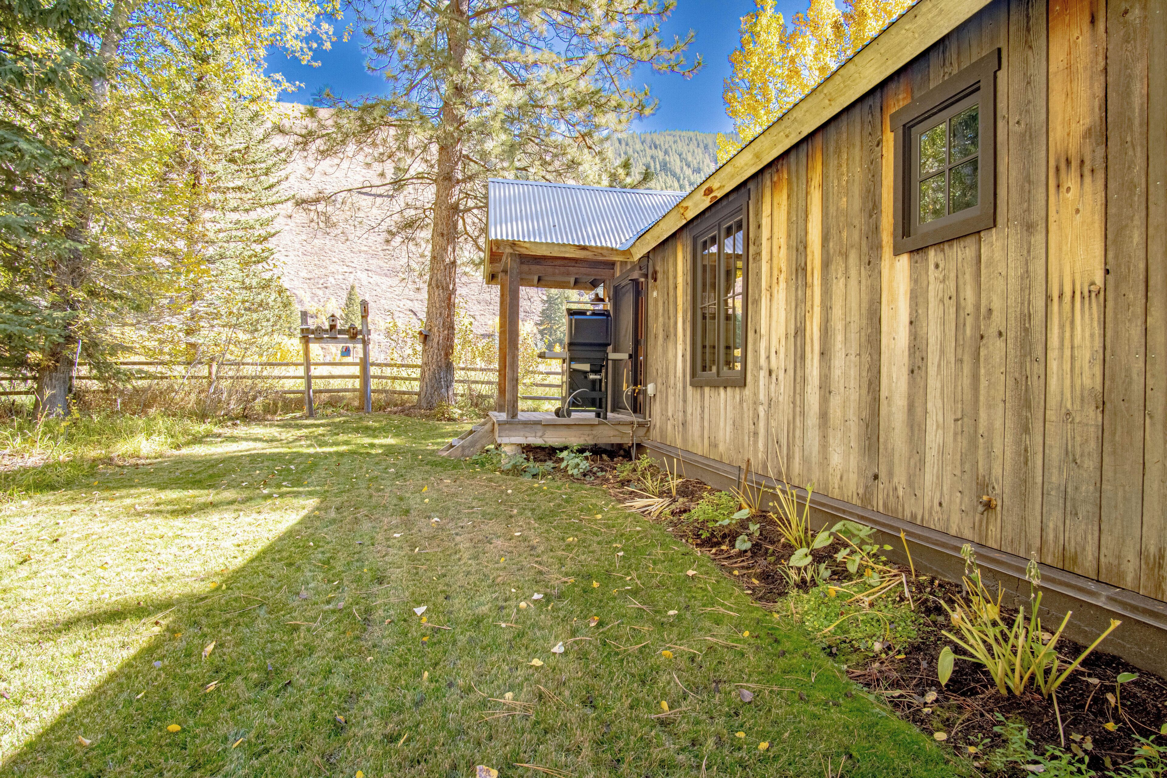 A wooden cabin with a covered porch, a metal roof, and a view of a mountain range.