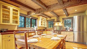 A spacious kitchen with wooden cabinets, a large dining table set for six, and a stainless steel refrigerator. - Board's Sunset Ranch - Sawtooth National Forest (Ketchum)