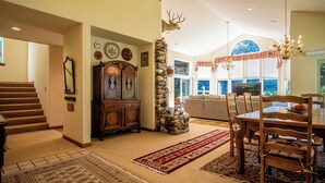 A spacious living area with a stone pillar, a wooden dining table with chairs, a large mirror, and a fireplace. - Sunflower Lane - 4BD Sun Valley Retreat + Resort Amenities (Sun Valley)