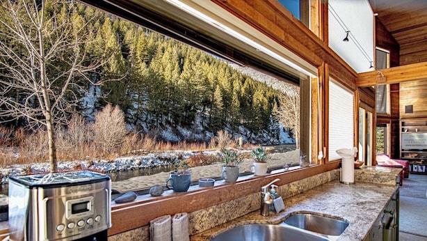 A modern kitchen with a stone countertop, stainless steel sinks, and a coffee maker. - River House - 4BD Riverfront, Hot Tub, Near SV Ski Lifts! (Ketchum)