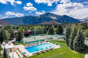 Un resort con piscina, canchas de tenis y montañas al fondo.