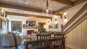 Un comedor con mesa y sillas de madera, una araña y una escalera que sube a un nivel superior.