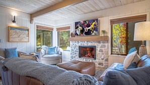 A cozy living room with a stone fireplace, comfortable seating, and a large TV mounted above it. - Creekside 1294 - Nr Ski + Sun Valley Rec Passes (Sun Valley)