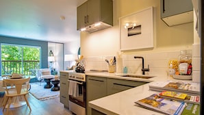 A modern kitchen with a large window, a dining area with a table and chairs, and a view of greenery outside. - Angani Studio - Elkhorn Resort Amenities Included (Sun Valley)