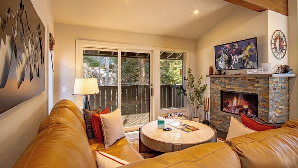 A living room with a leather couch, a round coffee table, a fireplace, and a television. - Stonehenge Condo - Nr Ski Lifts & Downtown! (Ketchum)