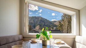 A dining table with bowls, glasses, and a potted plant, set against a window with a mountain view. - Stonehenge Condo - Nr Ski Lifts & Downtown! (Ketchum)