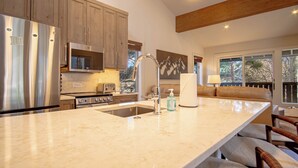 A kitchen with a large island, stainless steel appliances, wooden cabinets, and a view of the outdoors. - Stonehenge Condo - Nr Ski Lifts & Downtown! (Ketchum)