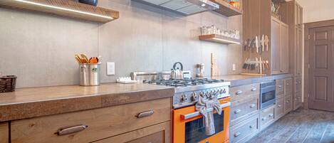 A kitchen with a large island, built-in oven, and stainless steel appliances.