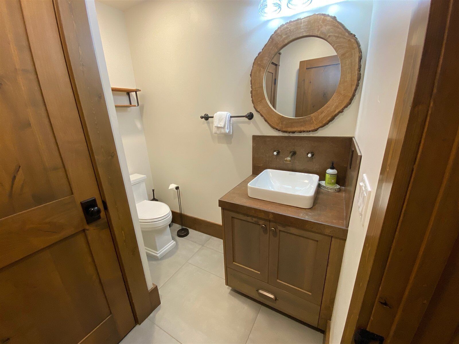 A bathroom with a toilet, sink, and mirror.