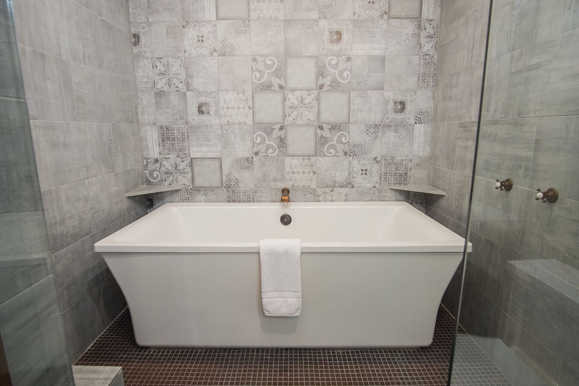 A bathroom with a freestanding bathtub, tiled walls, and a shower area.