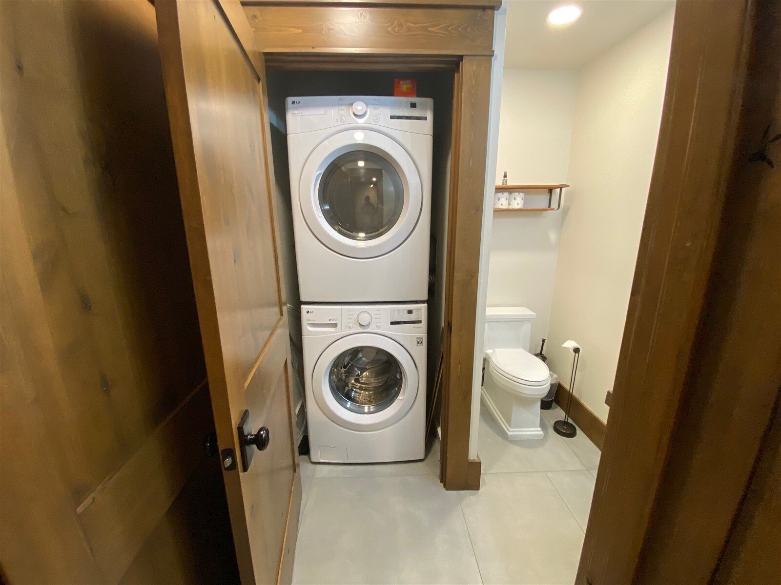 A compact laundry room with two stacked washing machines and a toilet.