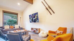A living room with a sofa, armchairs, a coffee table, and a television mounted on the wall. - DT Ketchum - Chill, Two-story Getaway w/ a Gourmet Kitchen - Walk Downtown & to River Run Lifts (Ketchum)