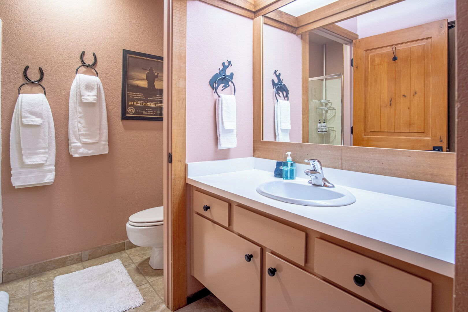 A bathroom with a white sink, a mirror, and two towels hanging on a wall.
