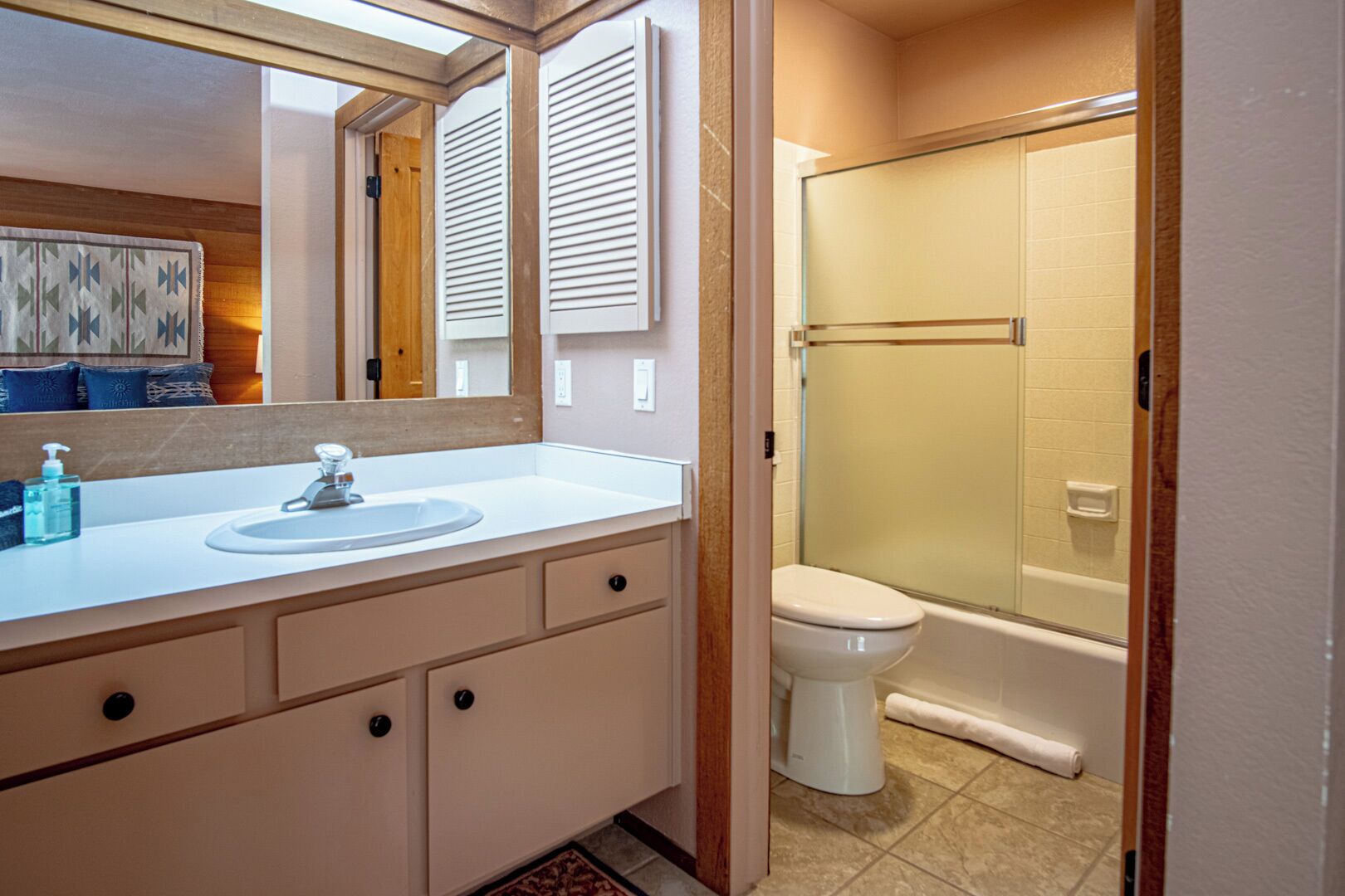 A bathroom with a sink, mirror, toilet, and glass-enclosed shower.