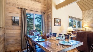 A wooden dining table with chairs, set for a meal, in a room with wooden walls and large windows. - 2BD Fairway Nine Golf Condo + Free Resort Amenities (Sun Valley)