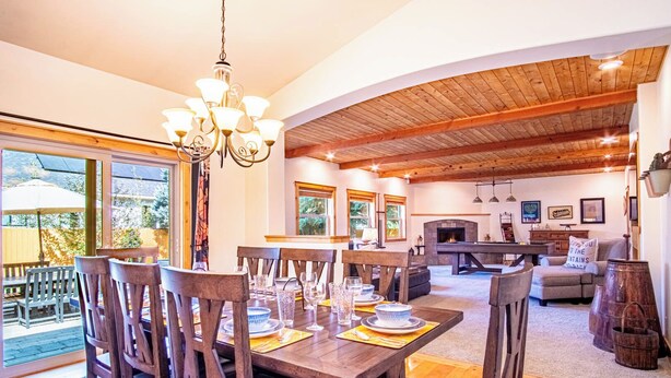A spacious dining area with wooden tables and chairs, a fireplace, and a cozy seating area with a sofa and armchairs. - Cranbrook Cottage - Family Home + Hot Tub + Pool Table (Hailey)