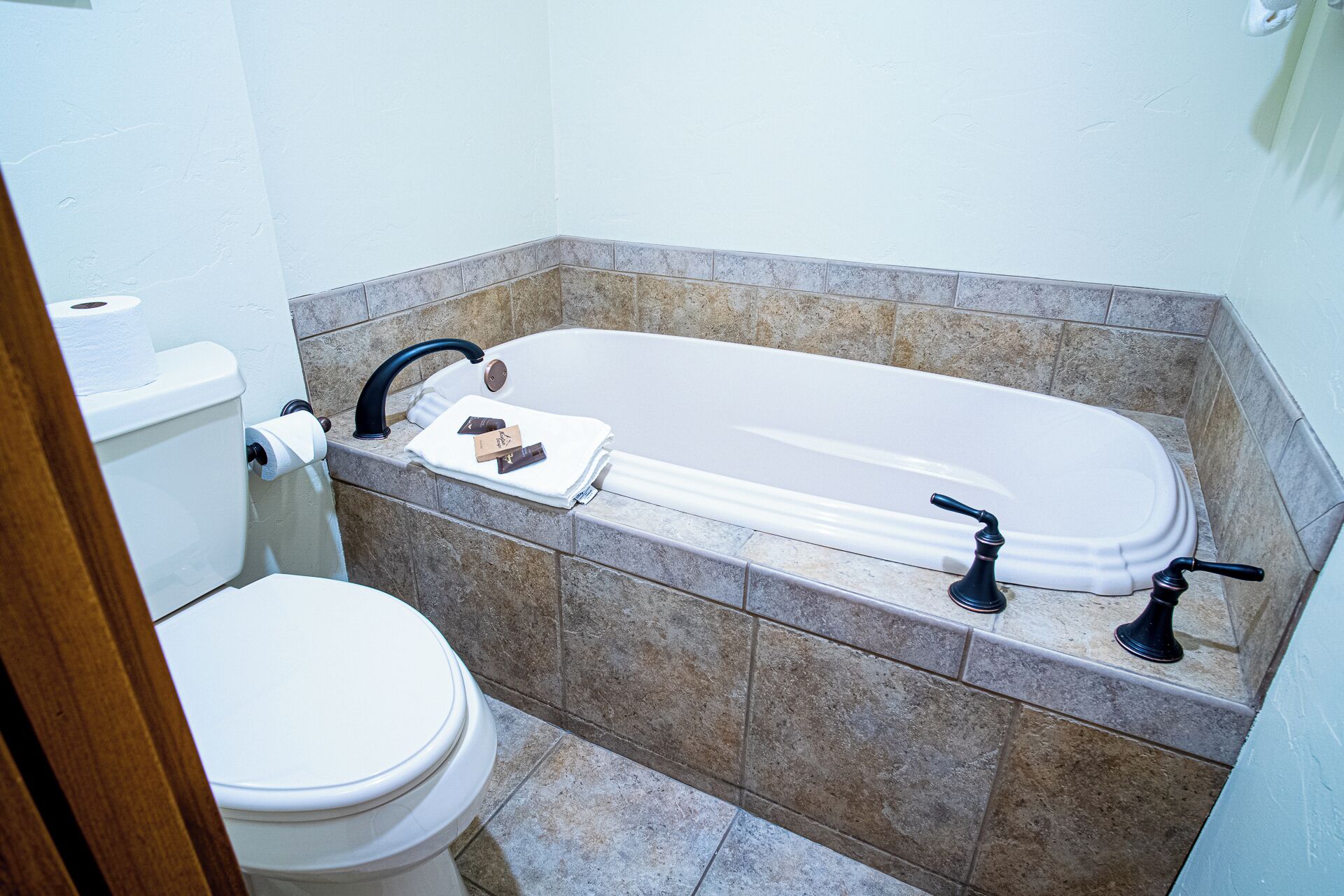 A bathroom with a bathtub, toilet, and a towel rack.