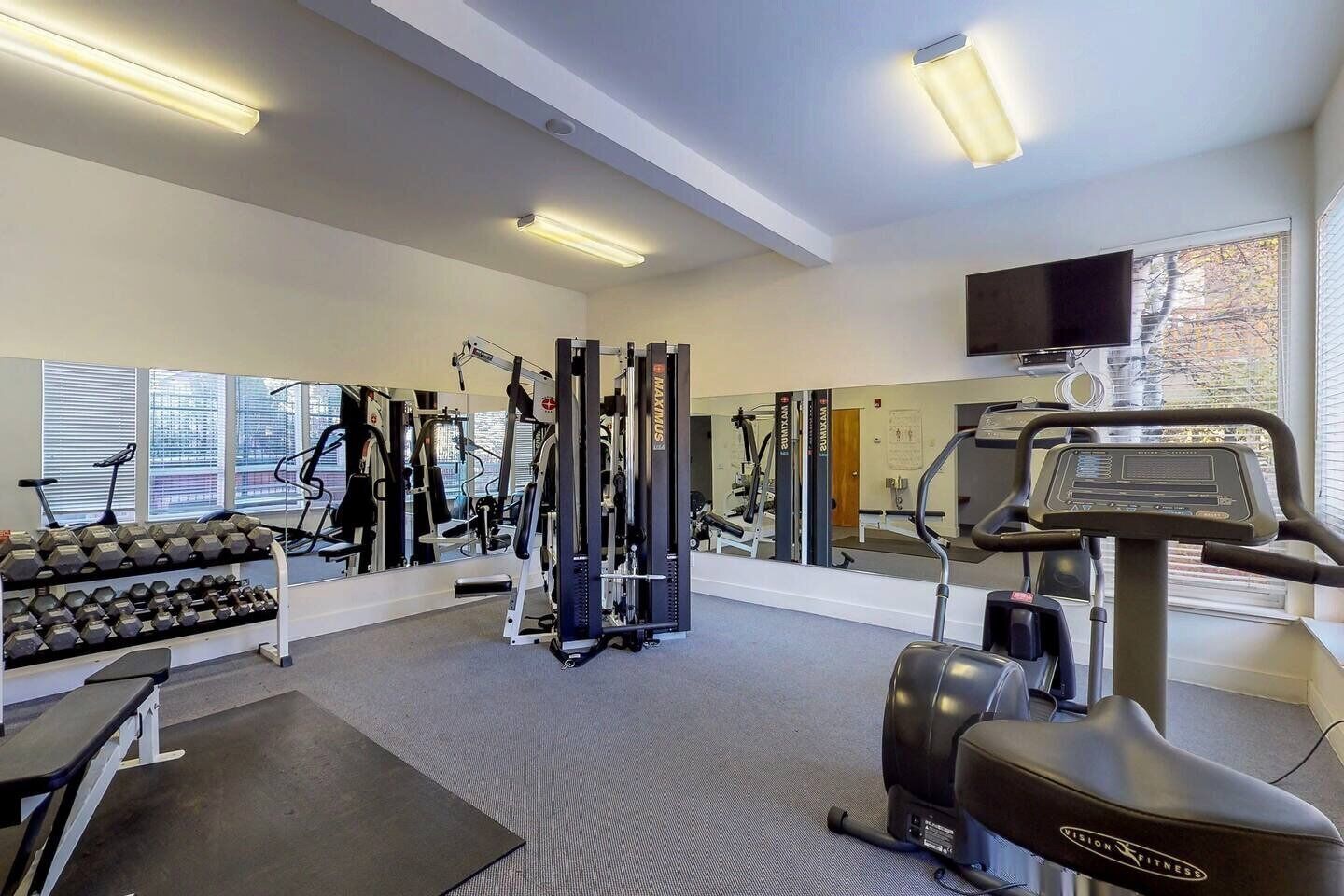Un gimnasio con equipo de ejercicio, una cinta de correr y mancuernas.