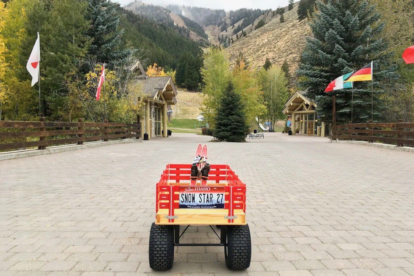 A snowmobile with a sign reading "Snow Star 27" in a paved area with wooden fences and flags.