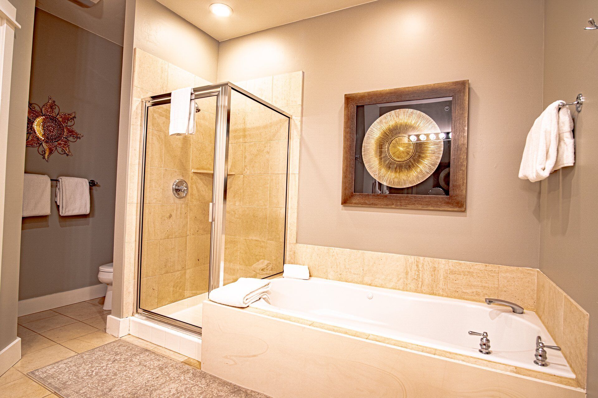 A modern bathroom with a glass-enclosed shower, a large bathtub, and a decorative mirror.