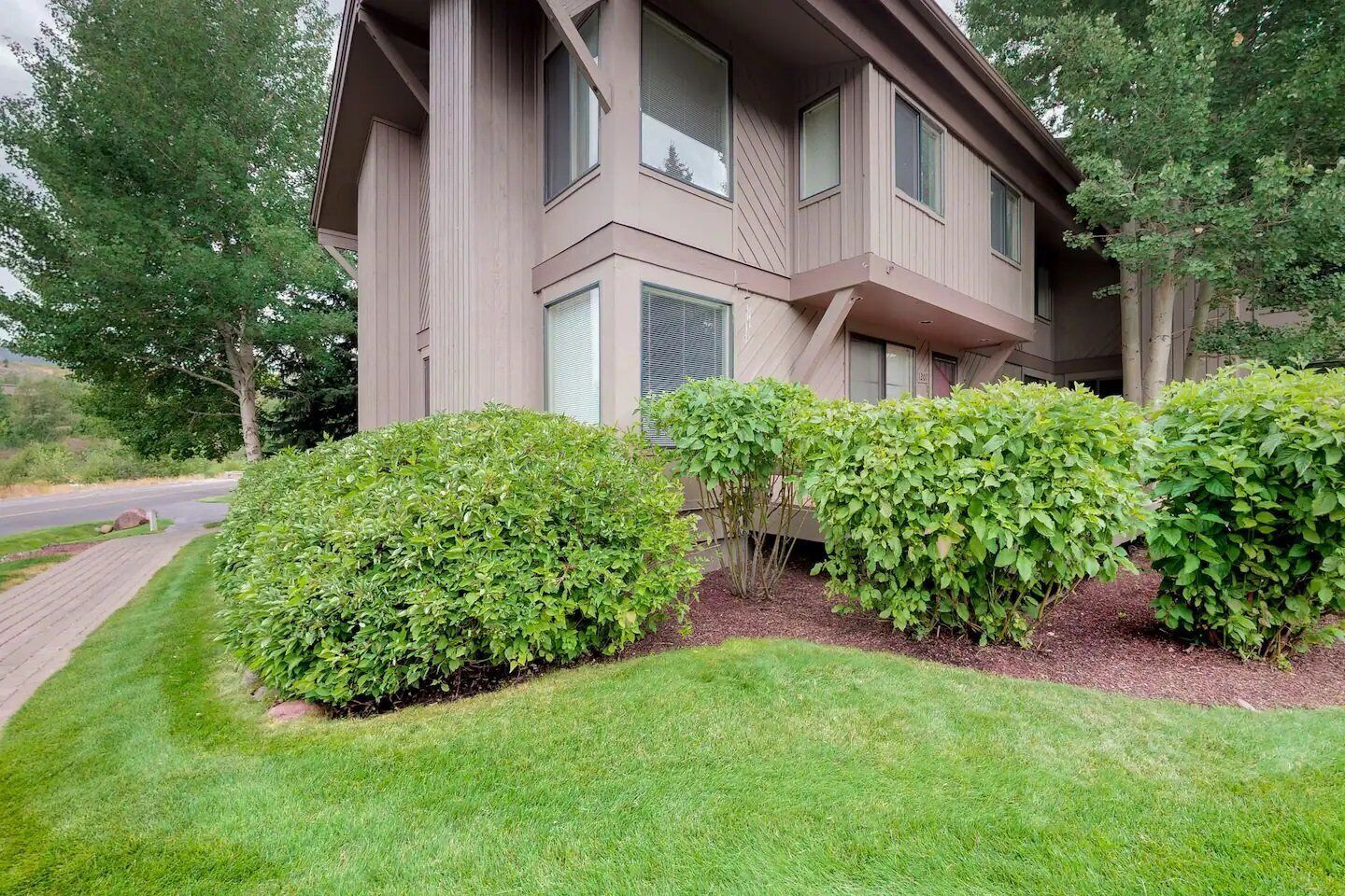 A two-story house with a front yard, a driveway, and a road in the background.