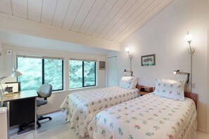 A bedroom with two beds, a desk, and a chair. There are windows with a view of trees. - Retro 3BD Sun Valley Condo + Free Resort Amenities! (Sun Valley)