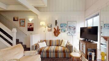 A living room with a striped sofa, a television, and framed pictures on the wall.