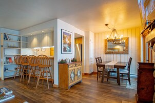 Una cocina moderna con armarios de madera, un comedor con mesa y sillas, y una araña.