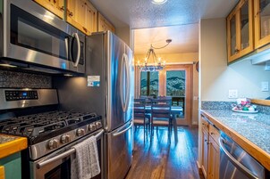 Una cocina moderna con electrodomésticos de acero inoxidable, armarios de madera y una araña.