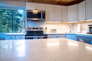 Uma cozinha moderna com armários brancos, eletrodomésticos de aço inoxidável e uma bancada grande de mármore.