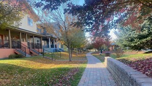 A residential street with a brick pathway, houses with front porches, and trees with autumn leaves. - 2BD Sweetwater Condo - Community Park, Pool + Hot Tub (Hailey)