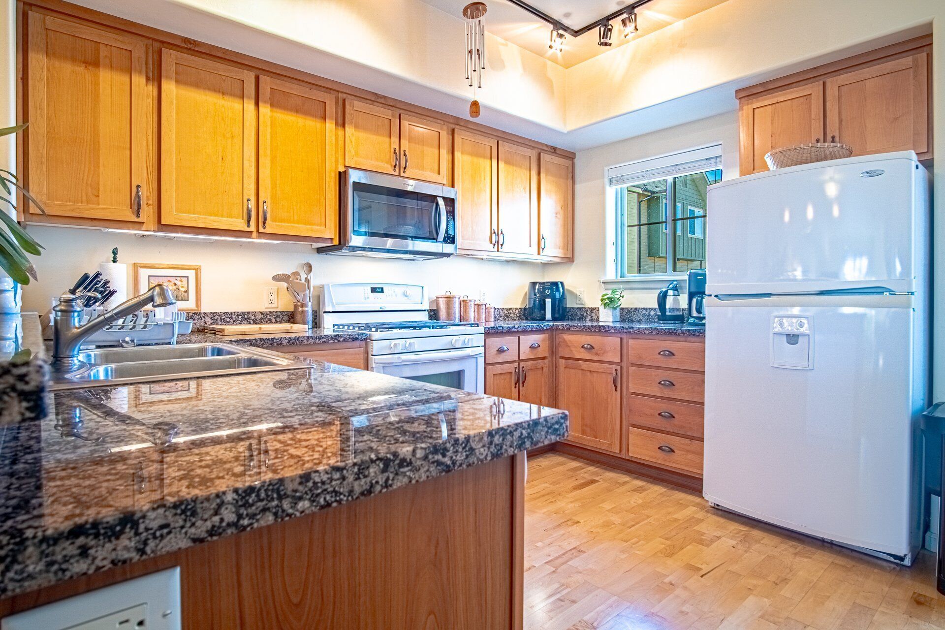 A kitchen with wooden cabinets, granite countertops, stainless steel appliances, and a window providing natural light.
