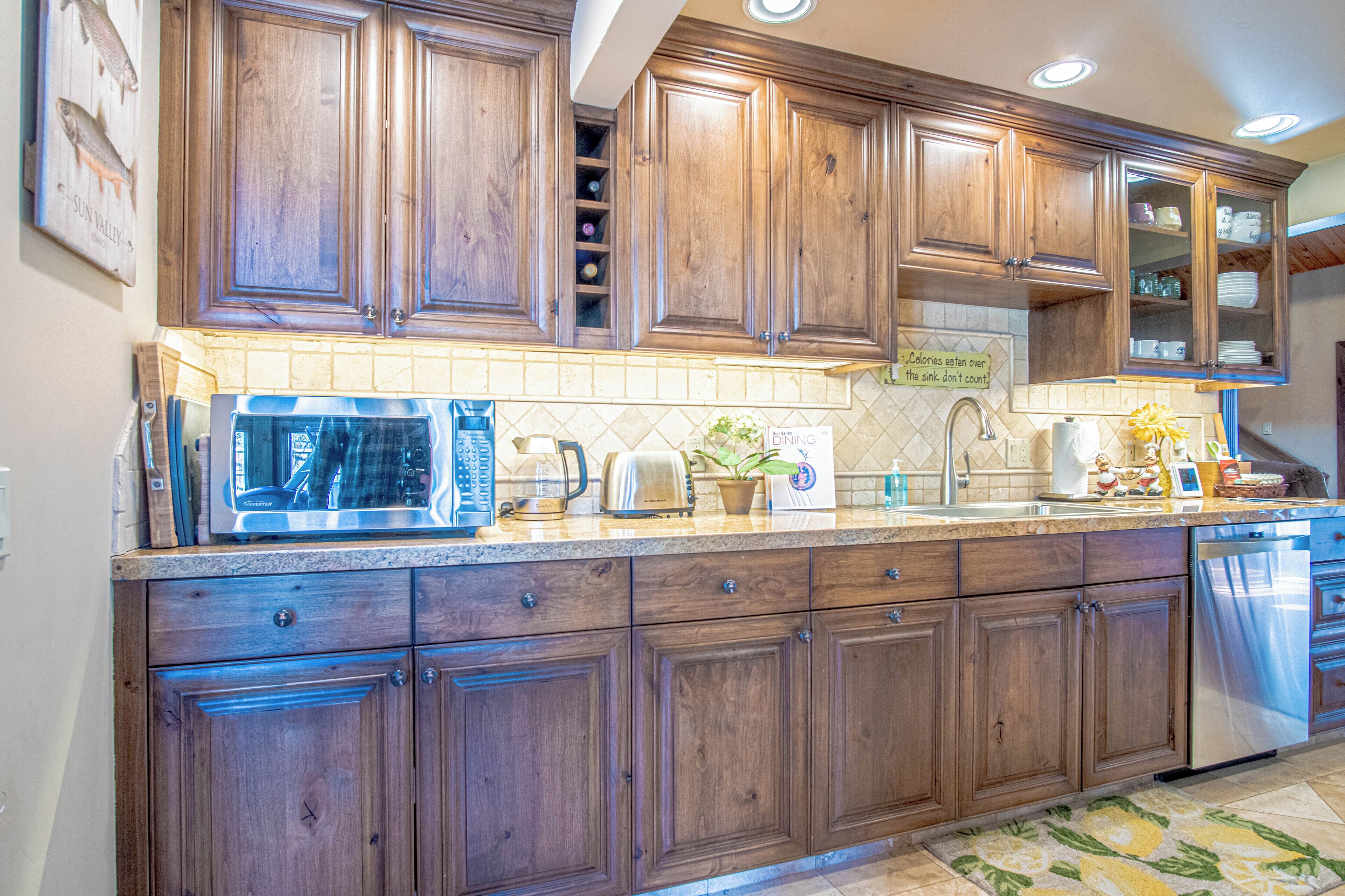 A kitchen with wooden cabinets, a microwave, toaster, sink, and dishwasher.