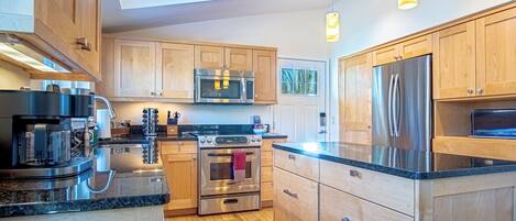 A modern kitchen with wooden cabinets, stainless steel appliances, and a skylight.