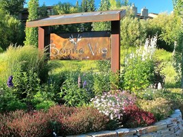 Um letreiro com o nome "Bonne Vie" cercado por um jardim com diversas plantas e flores.