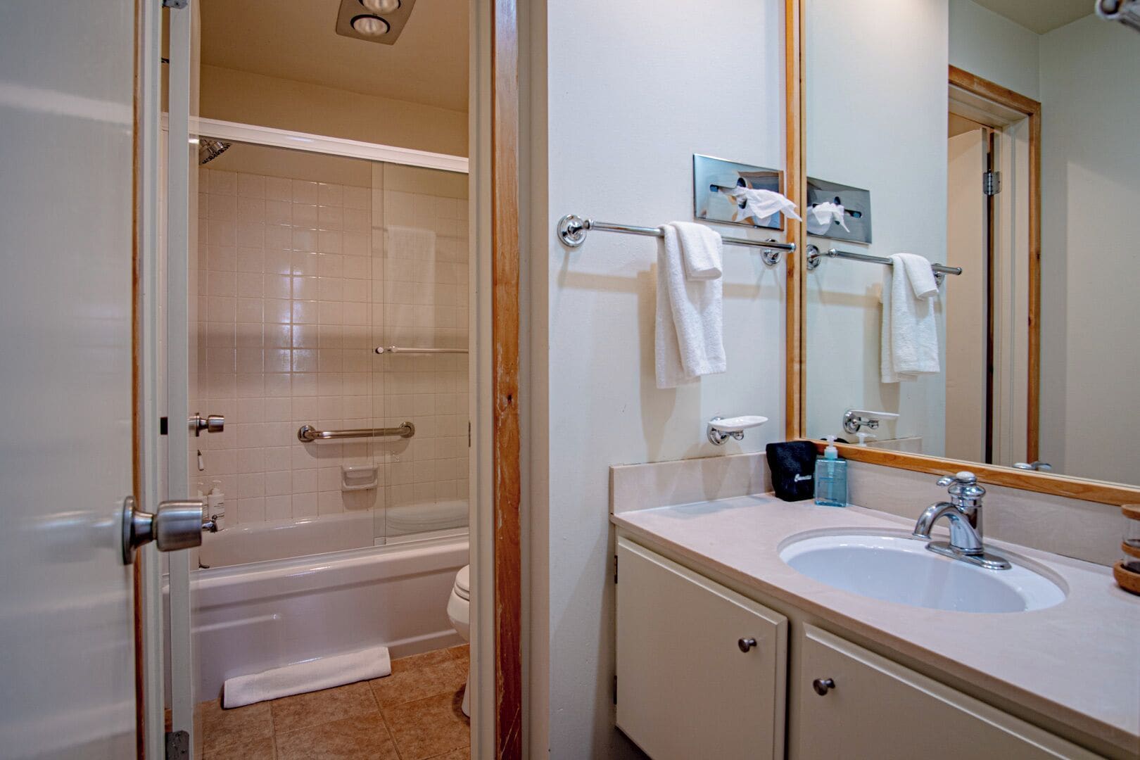 A bathroom with a bathtub, a shower, a sink, and a mirror.