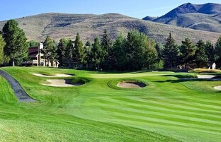 Um campo de golfe com bunkers e um clube de campo ao fundo.