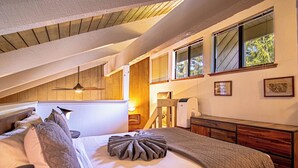 Une chambre à coucher comprenant un lit, une commode, une coiffeuse et une fenêtre avec des stores.