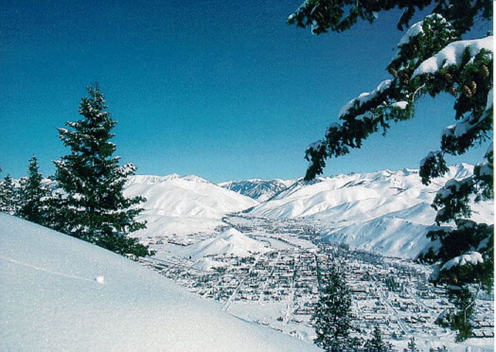 Eine verschneite Berglandschaft mit einer Stadt im Tal.