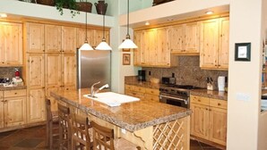 Eine Küche mit Holzausstattung, Granit Arbeitsplatten, einem Edelstahlkühlschrank und einem eingebauten Herd.