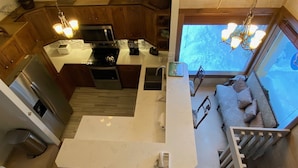Une cuisine moderne avec des meubles en bois, un îlot central et un coin repas comprenant un canapé et des coussins.
