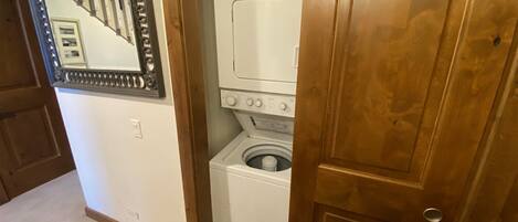 Une buanderie équipée d’un lave-linge et d’un sèche-linge, avec une porte en bois et un miroir accroché au mur.