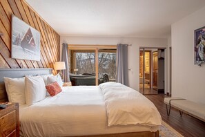A hotel room with a large bed, wooden headboard, a painting, a bench, and a view of the outdoors. - Ridge Condo - Modern Luxury Condo W/resort Amenities (Sun Valley)